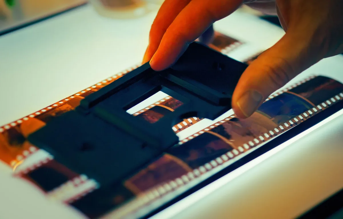 Analogfotograf arbeitet konzentriert mit Filmkamera und Belichtungsmesser