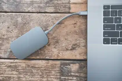 Hände verbinden Smartphone und Laptop mit USB-Kabel zur Fotodatenübertragung
