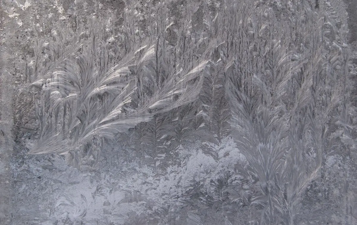 Wandbild mit gl&auml;nzender Kristalloberfl&auml;che in schwarzem Metallrahmen, das Licht reflektiert