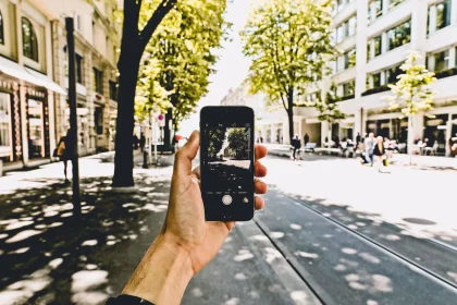 Person schaut auf Smartphone-Karte auf belebter Straße, unsicher wirkend