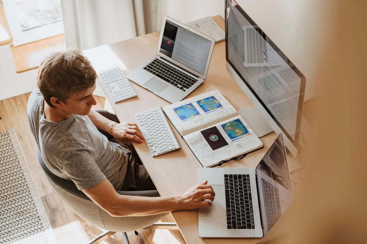 Junger Mensch arbeitet an kleinem Laptoptisch in Studentenwohnung