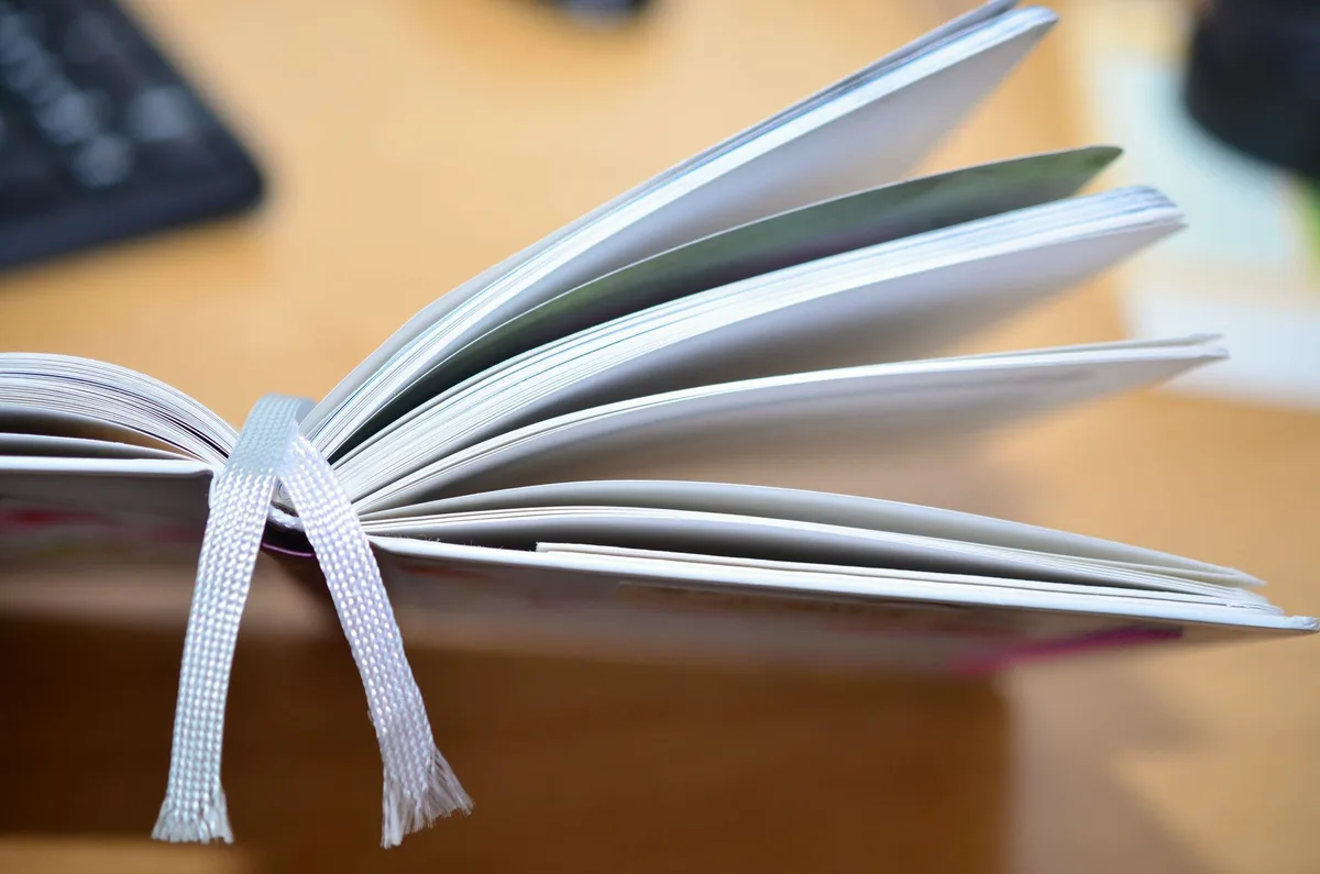 Handwerkliches Buchbinden mit natürlichen Materialien: Papier, Leim und Bindewerkzeuge auf einer Werkbank.