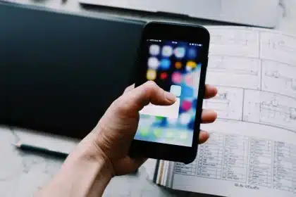 Smartphone mit Display nach unten auf einem Schreibtisch neben Kaffeetasse und Notizblock
