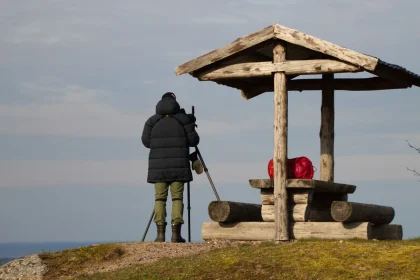 Fotograf mit Kamera auf Stativ in der Heide während eines Außeneinsatzes