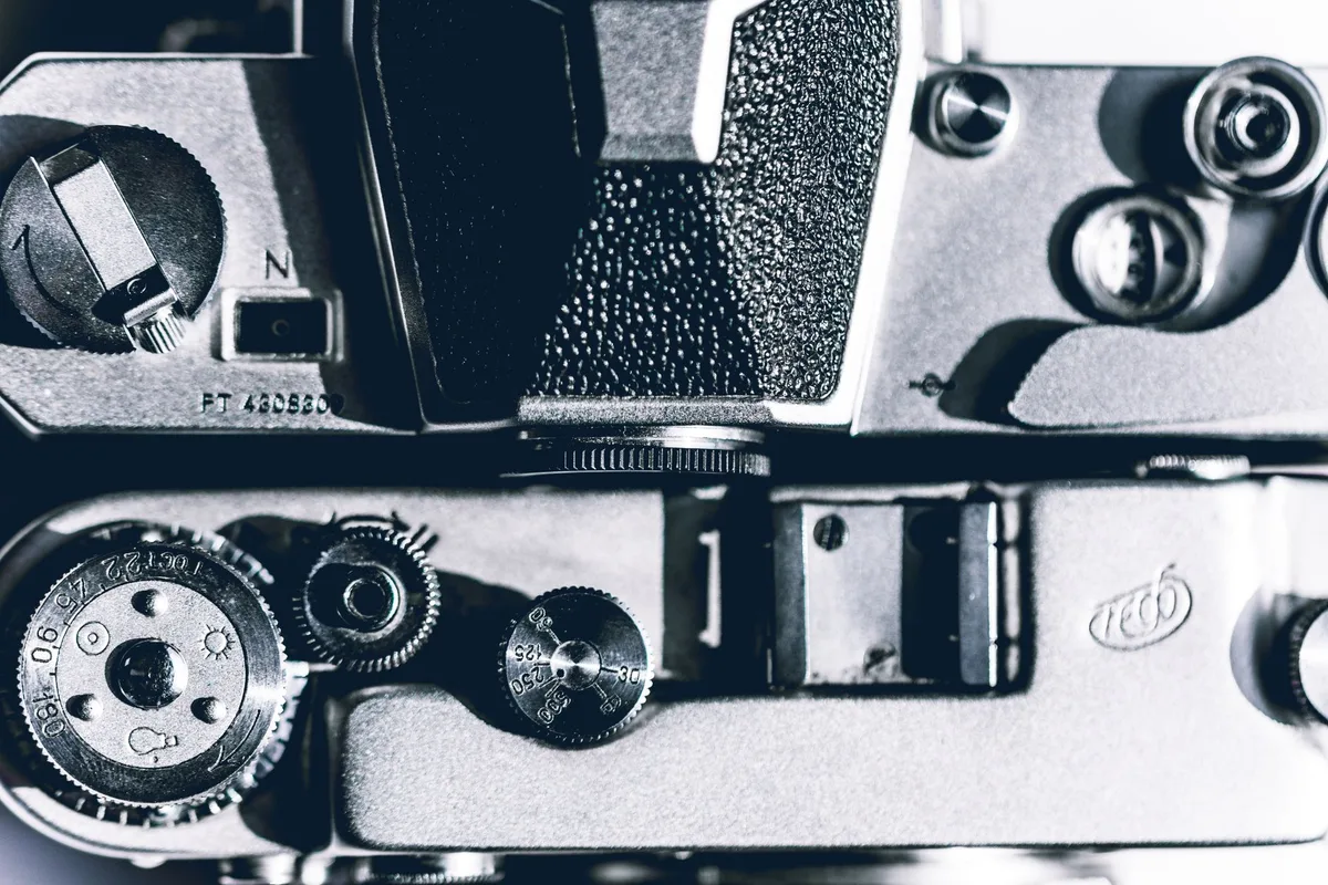 Detailaufnahme der manuellen Bedienelemente einer Analogkamera mit Blende und Verschlusszeit