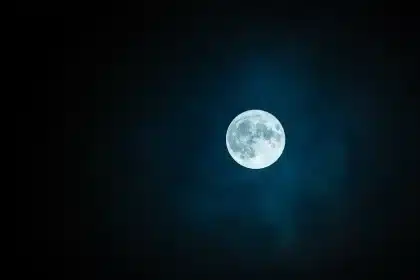 Fotograf hält Nachtfilter gegen Sternenhimmel mit Lichtverschmutzung am Horizont
