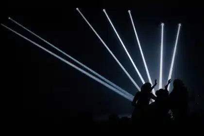 Silhouetten eines Publikums vor leerem DJ-Pult und Projektionen im Raum