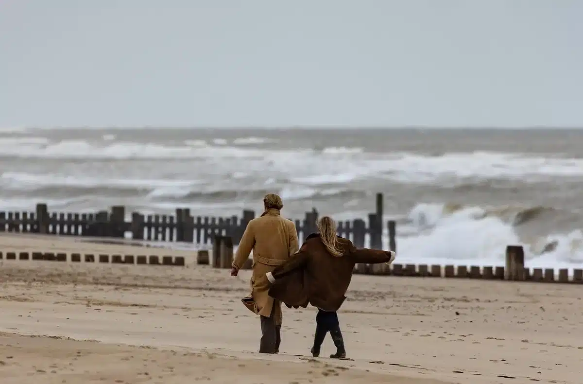 Paar bei Porträtaufnahmen auf schwarzem Sandstrand mit Bergkulisse im Hintergrund