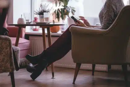 Smartphone mit geöffneter App-Übersicht auf einem Tisch, Hände im Hintergrund