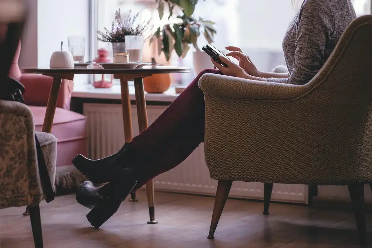 Smartphone mit geöffneter App-Übersicht auf einem Tisch, Hände im Hintergrund
