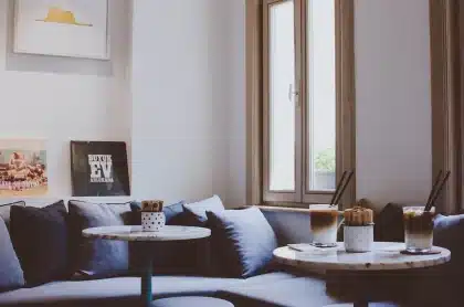 Stapel unterschiedlich gestalteter Fotobücher auf einem Holztisch in einer hellen Galerieecke