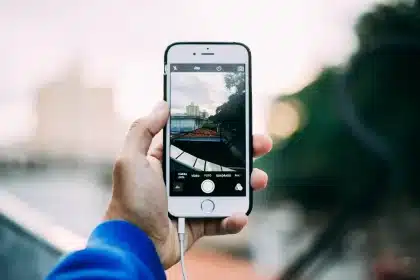 Hand hält Smartphone vor dampfiger Duschkabine, Glas mit Tropfen