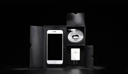 Unboxed Smartphone neben Verpackung und Prüfliste auf Tisch