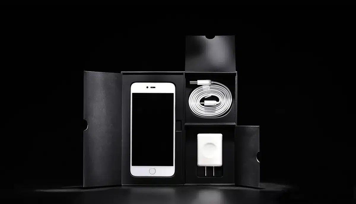 Unboxed Smartphone neben Verpackung und Prüfliste auf Tisch